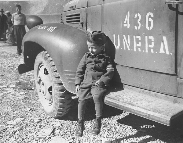 Четырехлетний бывший узник лагеря Бухенвальд около машины UNRRA, 1945 год - Sputnik Латвия