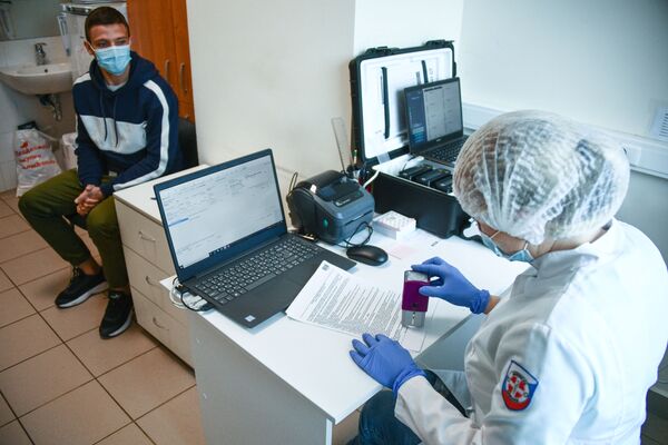 Сотрудник медицинской службы аэропорта Шереметьево проводит экспресс-тестирование пассажира на COVID-19 - Sputnik Латвия