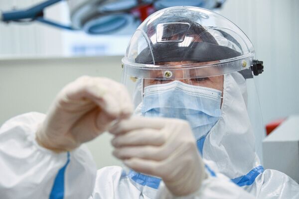 Сотрудник медицинской службы аэропорта Шереметьево проводит экспресс-тестирование на COVID-19 для пассажиров системой EMG - Sputnik Латвия