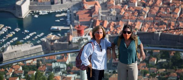 Tūristi aizsargmaskās pozē gaisa vagona augšējā stacijā virs Dubrovnikas vecpilsētas Horvātijā. Tūristi aizsargmaskās pozē gaisa vagona augšējā stacijā virs Dubrovnikas vecpilsētas Horvātijā. - Sputnik Latvija