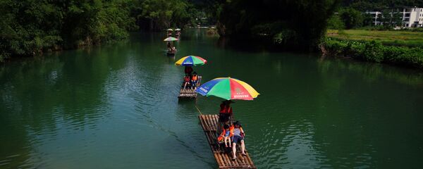 Туристы катаются на плотах по реке Юлонг в округе Яншо, Гуанси-Чжуанский автономный район, Китай - Sputnik Латвия