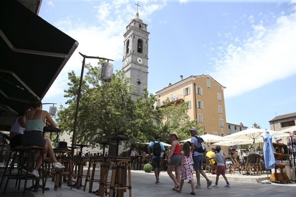 Туристы гуляют перед церковью Сен-Жан-Батист на главной площади старого города Порто-Веккио, на французском средиземноморском острове Корсика - Sputnik Латвия