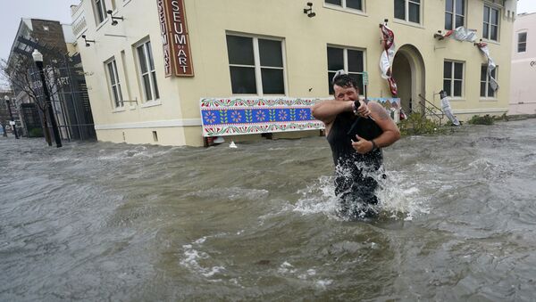Мужчина на затопленной улице города Пенсакола в штате Флорида во время урагана Салли - Sputnik Латвия