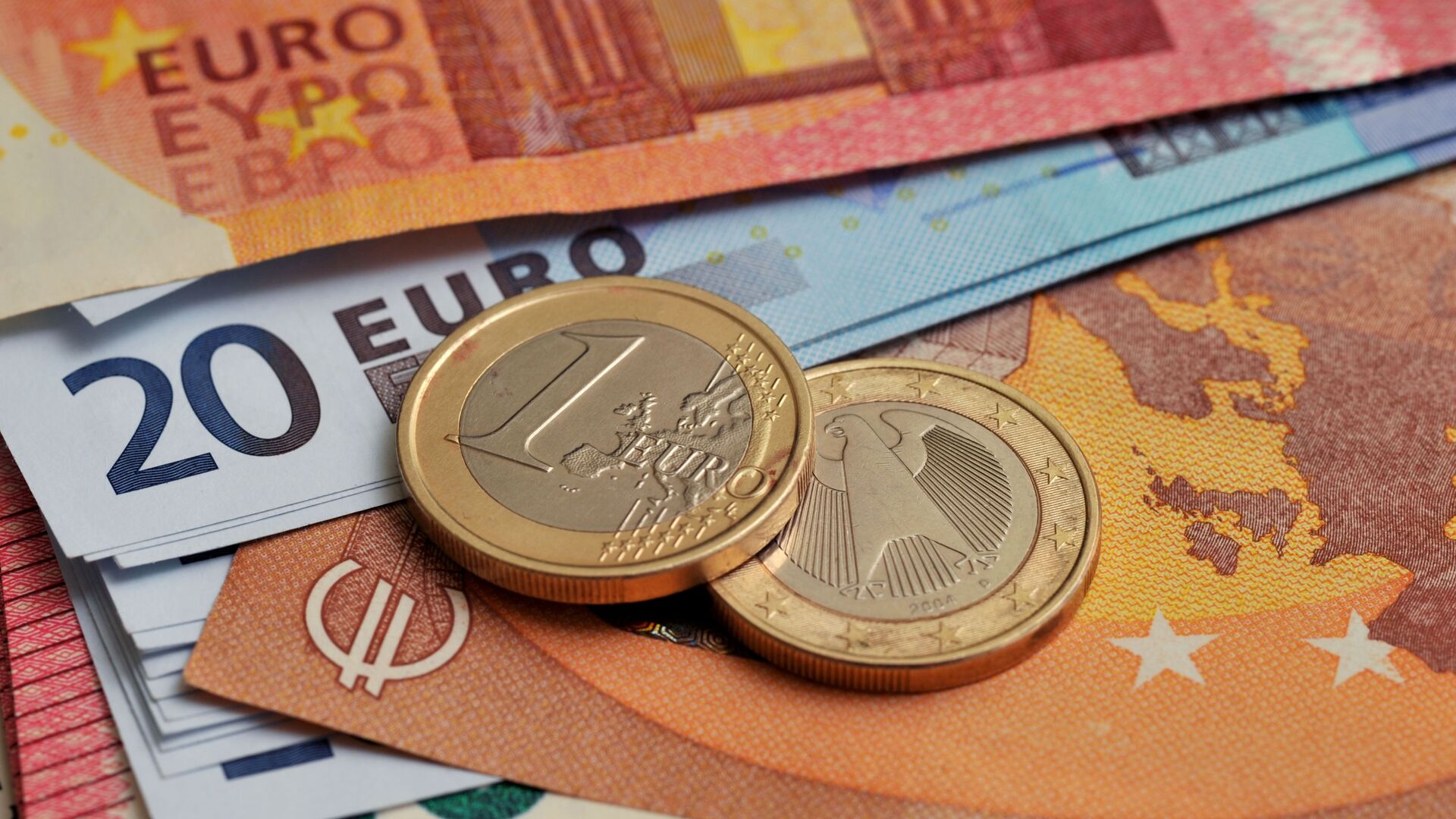 Монеты номиналом 1 евро на фоне банкнот номиналом 10 и 20 евро - Sputnik Латвия, 1920, 07.08.2021