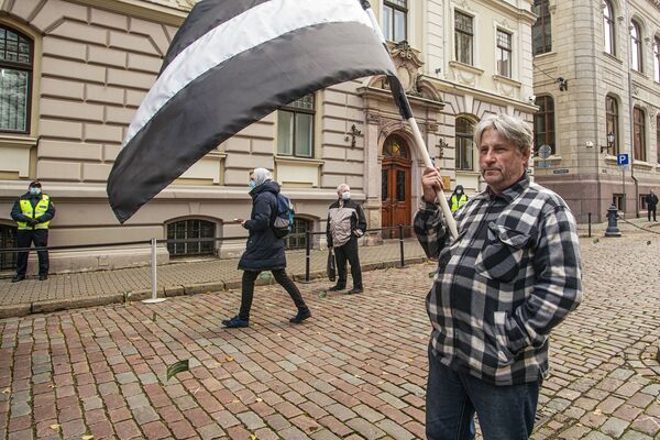 Протестующий с флагом Латвии в траурной расцветке - Sputnik Латвия