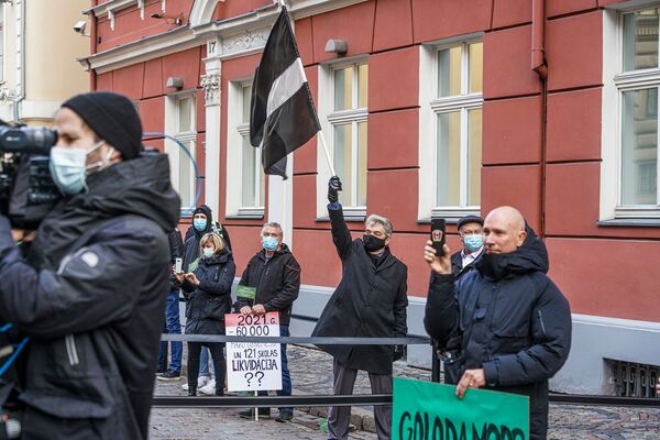Протестующий поднимает флаг Латвии в траурной расцветке - Sputnik Латвия