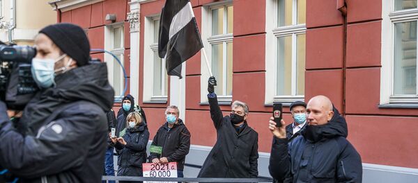 Протестующий поднимает флаг Латвии в траурной расцветке - Sputnik Латвия