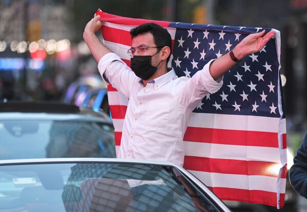 Человек с флагом США на Таймс-сквер в Нью-Йорке после новостей о победе на выборах президента США кандидата от Демократической партии Джозефа Байдена - Sputnik Латвия