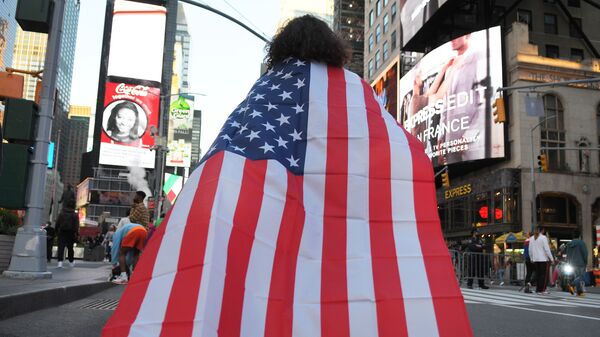 Человек на одной из улиц Нью-Йорка с государственным флагом США - Sputnik Латвия