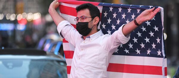 Человек с флагом США на Таймс-сквер в Нью-Йорке после новостей о победе на выборах президента США кандидата от Демократической партии Джозефа Байдена Человек с флагом США на Таймс-сквер в Нью-Йорке после новостей о победе на выборах президента США кандидата от Демократической партии Джозефа Байдена - Sputnik Latvija