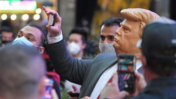 Люди на Таймс-сквер в Нью-Йорке фотографируют человека в маске Дональда Трампа - Sputnik Латвия