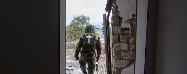 Военнослужащий возле дома, поврежденного в результате обстрела Степанакерта во время обострения конфликта в Нагорном Карабахе - Sputnik Латвия