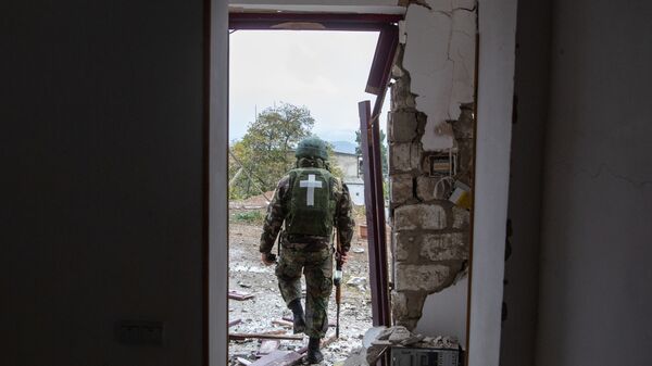 Военнослужащий возле дома, поврежденного в результате обстрела Степанакерта во время обострения конфликта в Нагорном Карабахе - Sputnik Латвия