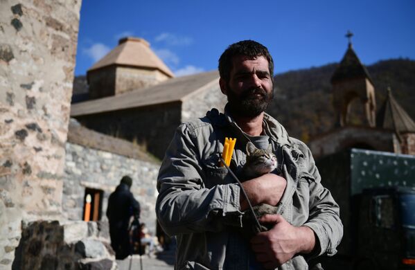 Vīrietis ar kaķi rokās pie baznīcas Dadivankas klosterī Kalnu Karabahā - Sputnik Latvija