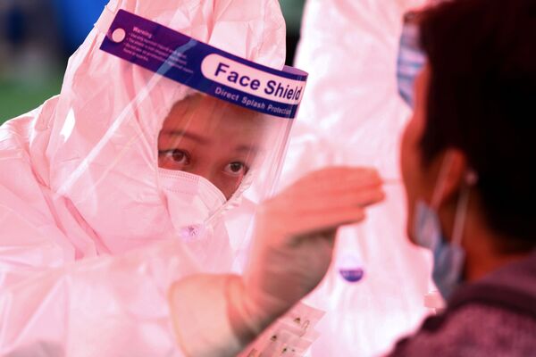 Медицинский работник берет мазок у местного жителя в рамках программы массового тестирования в Циндао в восточной провинции Шаньдун, Китай  - Sputnik Латвия