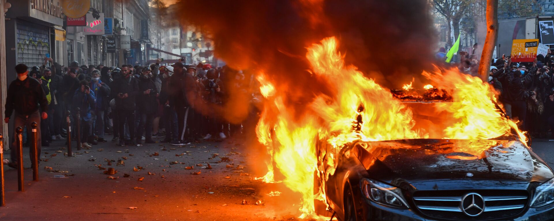 Горящий автомобиль во время акции недовольства действиями правоохранительных органов в отношении мигрантов и против внесения поправки к закону О национальной безопасности в Париже - Sputnik Латвия, 1920, 18.02.2026