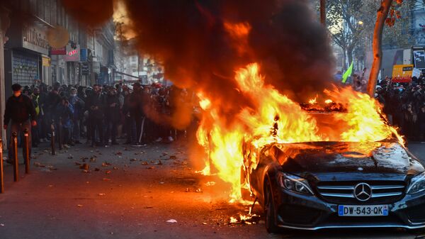 Горящий автомобиль во время акции недовольства действиями правоохранительных органов в отношении мигрантов и против внесения поправки к закону О национальной безопасности в Париже - Sputnik Латвия