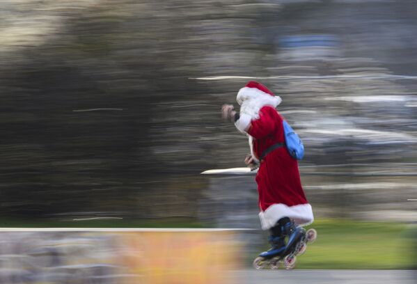Человек в костюме Санта-Клауса едет на роликовых коньках по центру немецкого города Дрезден - Sputnik Латвия