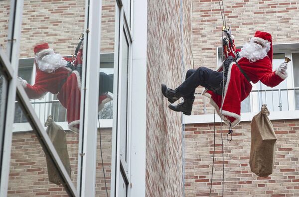 Спасатель в костюме Санта-Клауса спускается с крыши детской больницы в немецком Гамбурге - Sputnik Латвия