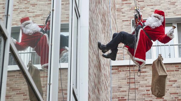 Спасатель в костюме Санты-Клауса спускается с крыши детской больницы в Германии  - Sputnik Латвия
