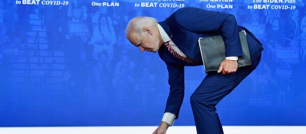 Кандидат в президенты США Джо Байден наклоняется за упавшей медицинской маской Кандидат в президенты США Джо Байден наклоняется за упавшей медицинской маской - Sputnik Latvija