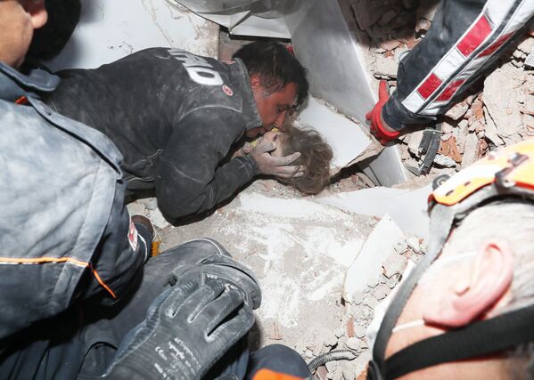 Турецкие спасатели вытаскивают ребенка из-под обломков после землетрясения в Измире - Sputnik Латвия