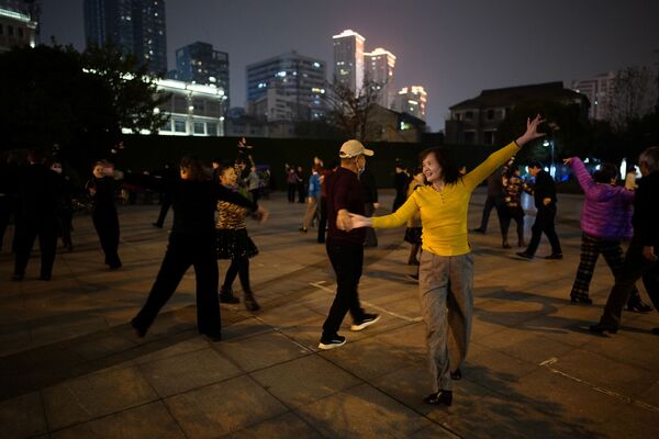 Люди танцуют ночью парке спустя год после вспышки COVID-19 в Ухане - Sputnik Латвия