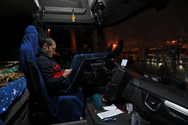 Румынский водитель сидит в кабине своего грузовика, припаркованного на стоянке у автомагистрали M20, ведущей в Дувр - Sputnik Латвия