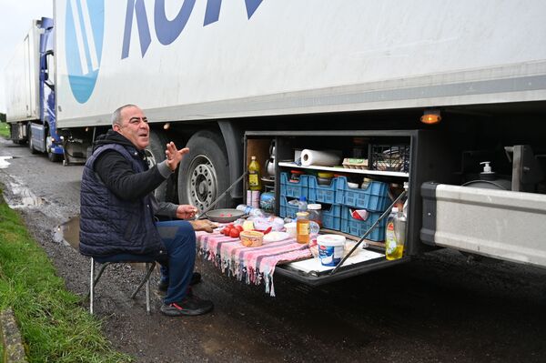 Турецкий водитель-дальнобойщик завтракает на стоянке для грузовиков у автомагистрали M20 на юго-востоке Англии - Sputnik Латвия