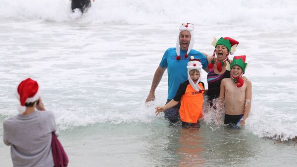 Люди в рождественской одежде позируют для фотографий в Рождество на пляже Бонди в Сиднее, Австралия - Sputnik Латвия