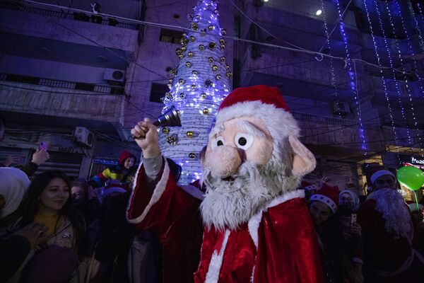 Мужчина в костюме Санта-Клауса во время празднования Рождества в сирийском городе Эль-Камышлы - Sputnik Латвия