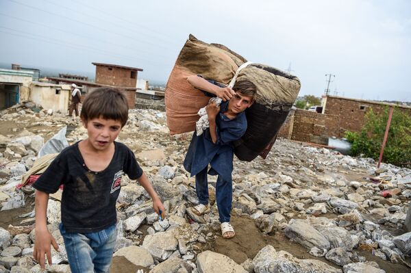 Bērni glābj mantas no mājas drupām pēc plūdiem 26. augustā Afganistānā. Tie aiznesa 190 cilvēku dzīvības, cietuši 172 cilvēki - Sputnik Latvija