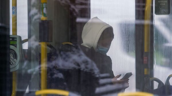 Женщина в маске в общественном транспорте в Риге - Sputnik Латвия