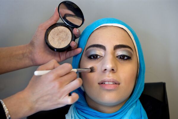 Молодая девушка в хиджабе делает макияж, готовясь к выпускному вечеру в старшей школе в Джермантуане, США - Sputnik Латвия