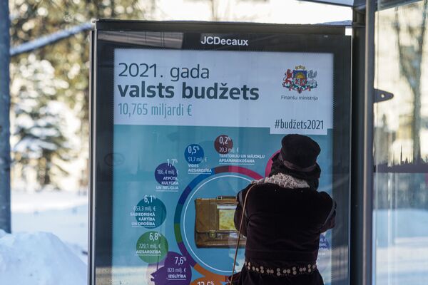Информационный плакат на остановке общественного транспорта о расходах латвийского бюджета в 2021 году - Sputnik Латвия