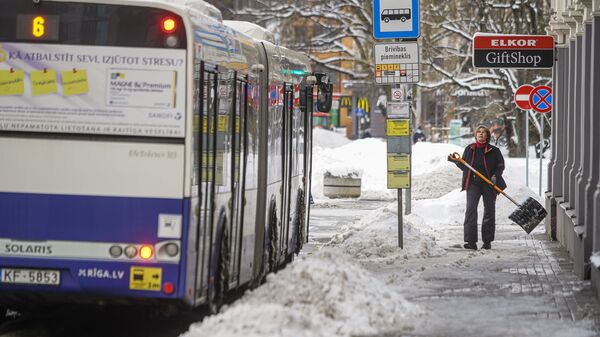 Женщина убирает снег на остановке общественного транспорта - Sputnik Латвия