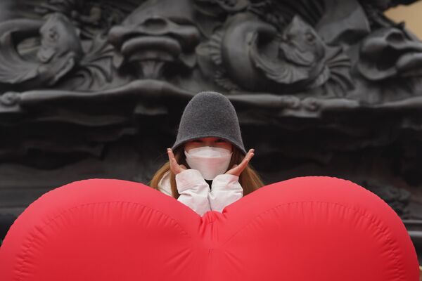Девушка в маске фотографируется возле воздушного шара в форме сердца в Пекине, Китай - Sputnik Латвия