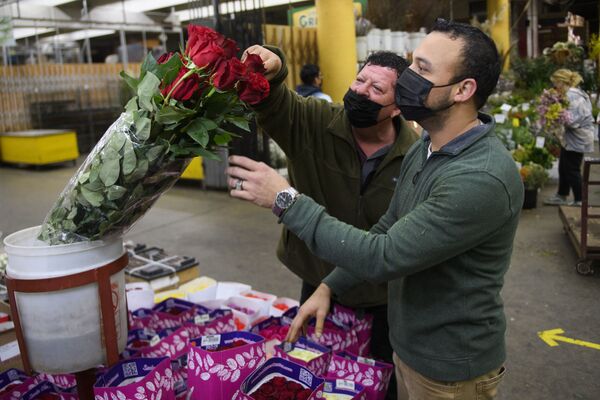 Торговец помогает выбрать букет покупателю в преддверии Дня святого Валентина на цветочном рынке в Лос-Анджелесе, Калифорния - Sputnik Латвия