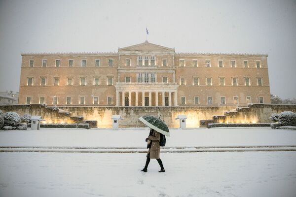 Женщина с зонтиком проходит мимо здания парламента во время сильного снегопада в Афинах, Греция - Sputnik Латвия