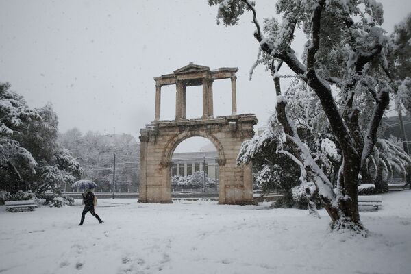 Пешеход идет рядом с воротами Адриана во время сильного снегопада в Афинах, Греция - Sputnik Латвия