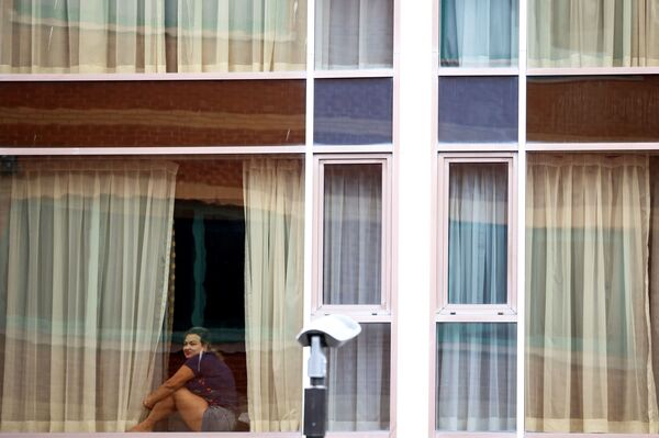 Женщина смотрит из окна отеля Radisson Blu в лондонском аэропорту Хитроу - Sputnik Латвия