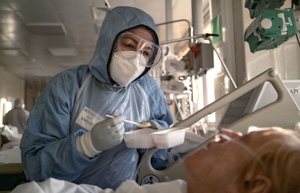 Medicīnas māsa ēdina pacientu reanimācijas un intensīvās terapijas nodaļā slimnīcā Maskavā - Sputnik Latvija