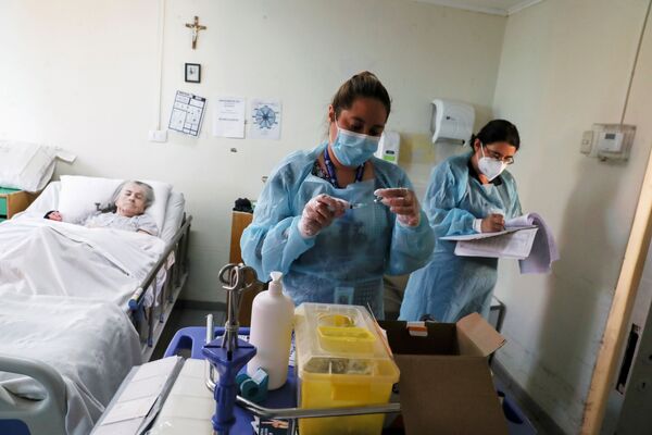 Медицинские работники в доме престарелых в Сантьяго перед вакцинацией от коронавируса пожилой пациентки - Sputnik Латвия
