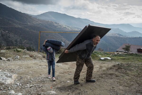 Мурад Мвргарян и его сын Ваак выносят вещи из своего дома перед тем, как покинуть город Лачин - Sputnik Латвия