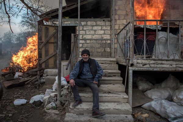 Местный житель Арег сидит у горящего дома в поселке Карегах, Нагорный Карабах. Некоторые жители сожгли свои дома, перед тем как уйти - Sputnik Латвия
