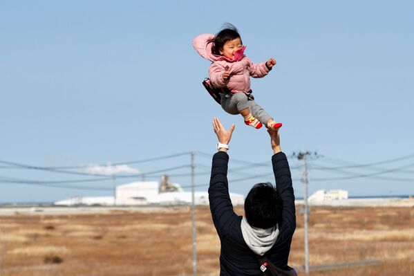 Потерявший родных во время землетрясения 2011 года отец с ребенком в префектуре Фукусима  - Sputnik Латвия