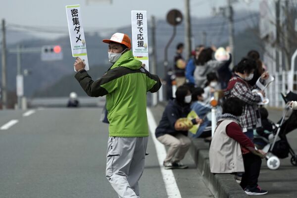 Мужчина с табличками во время эстафеты олимпийского огня в Токио-2020 в префектуре Фукусима, Япония - Sputnik Латвия