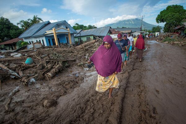 Люди идут по грязи в индонезийской провинции Восточная Нуса - Тенгара, которая пострадала от тропического циклона - Sputnik Латвия