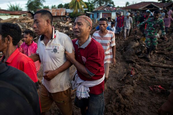 Cilvēki apraud stihijas nelaimē bojāgājušos tuviniekus Austrumnusas-Tengaras provincē Indonēzijā - Sputnik Latvija