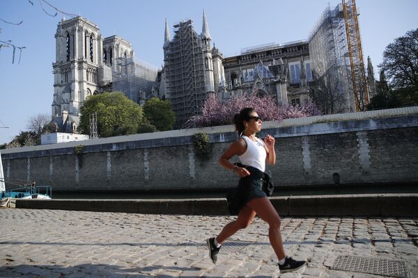 Meitene skrien Parīzes Dievmātes katedrāles fonā restaurācijas laikā - Sputnik Latvija